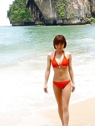 Japanese Yumiko Shaku in orange bath suit takes a walk on the beach